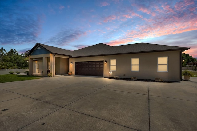 view of front of home featuring a garage, fence, stucco siding, and driveway