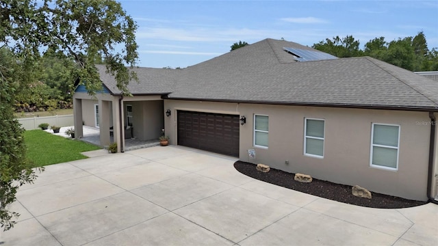 view of home's exterior featuring a garage, stucco siding, concrete driveway, and roof with shingles