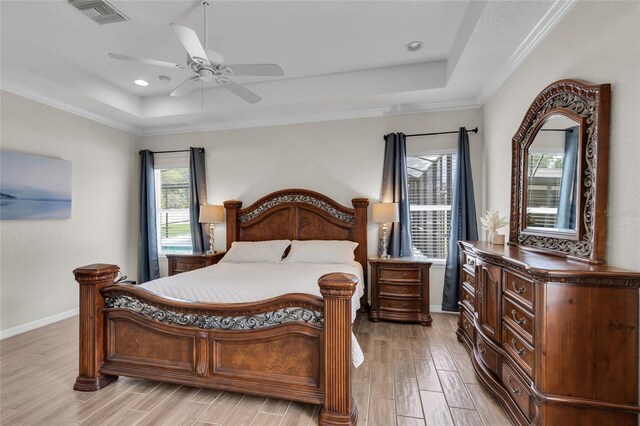 bedroom featuring light wood finished floors, visible vents, and a raised ceiling
