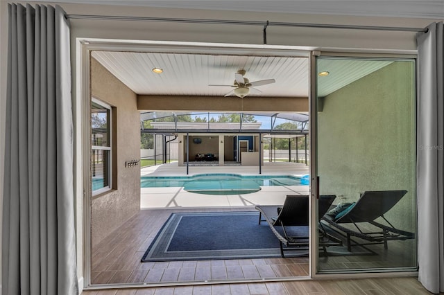 outdoor pool with a patio, ceiling fan, and glass enclosure