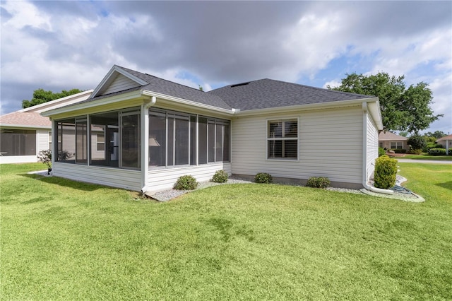 rear view of property featuring a sunroom, a shingled roof, and a yard