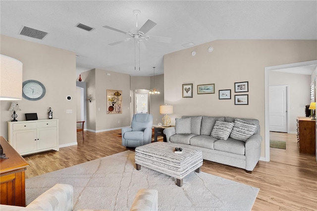 living room with ceiling fan, visible vents, vaulted ceiling, and light wood-style floors