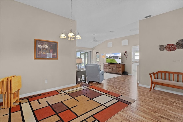 interior space with ceiling fan with notable chandelier, baseboards, wood finished floors, vaulted ceiling, and visible vents