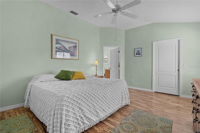 bedroom featuring a textured ceiling, baseboards, vaulted ceiling, and wood finished floors