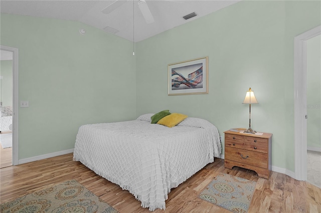 bedroom with visible vents, baseboards, lofted ceiling, and wood finished floors