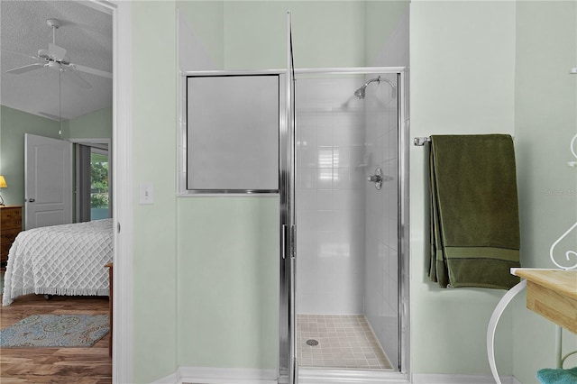 ensuite bathroom with wood finished floors, lofted ceiling, ceiling fan, connected bathroom, and a shower stall