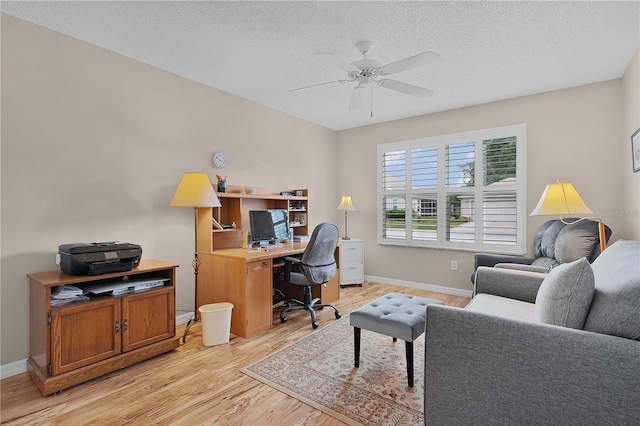 home office featuring a textured ceiling, ceiling fan, baseboards, and light wood-style floors