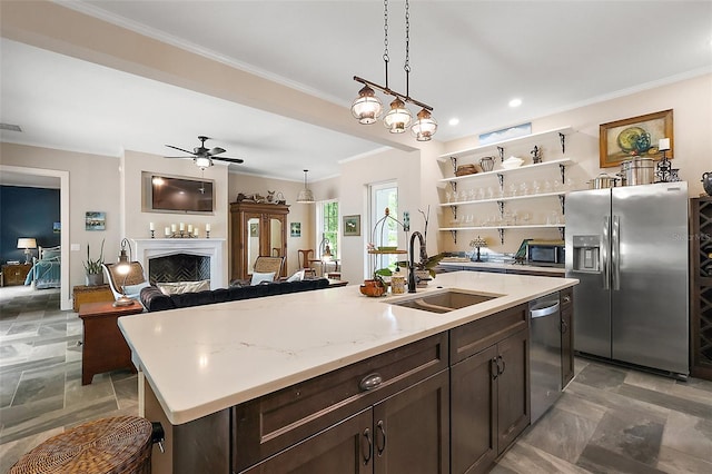6905 Clayton St, Mount Dora, FL 32757 - kitchen featuring stainless steel appliances, a sink, a fireplace, crown molding, and dark brown cabinetry