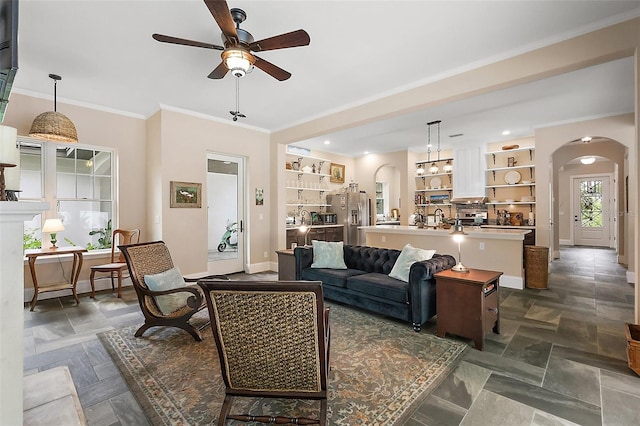 6905 Clayton St, Mount Dora, FL 32757 - living room with arched walkways, a ceiling fan, baseboards, crown molding, and dark stone finish flooring