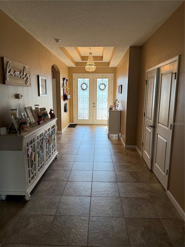 entryway with arched walkways, baseboards, french doors, and a textured ceiling
