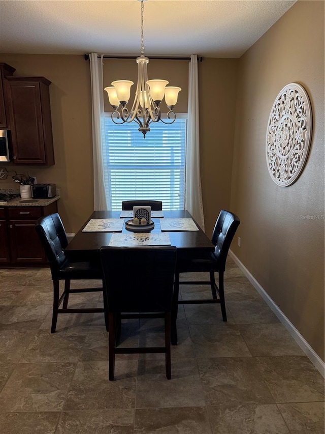 dining area featuring a chandelier and baseboards