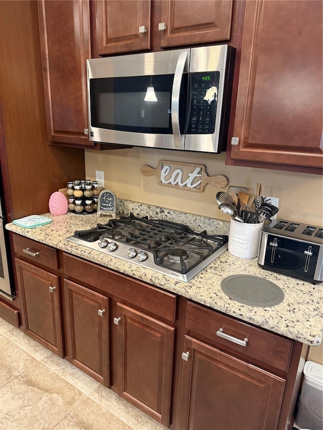 kitchen with light stone counters, light tile patterned floors, and stainless steel appliances