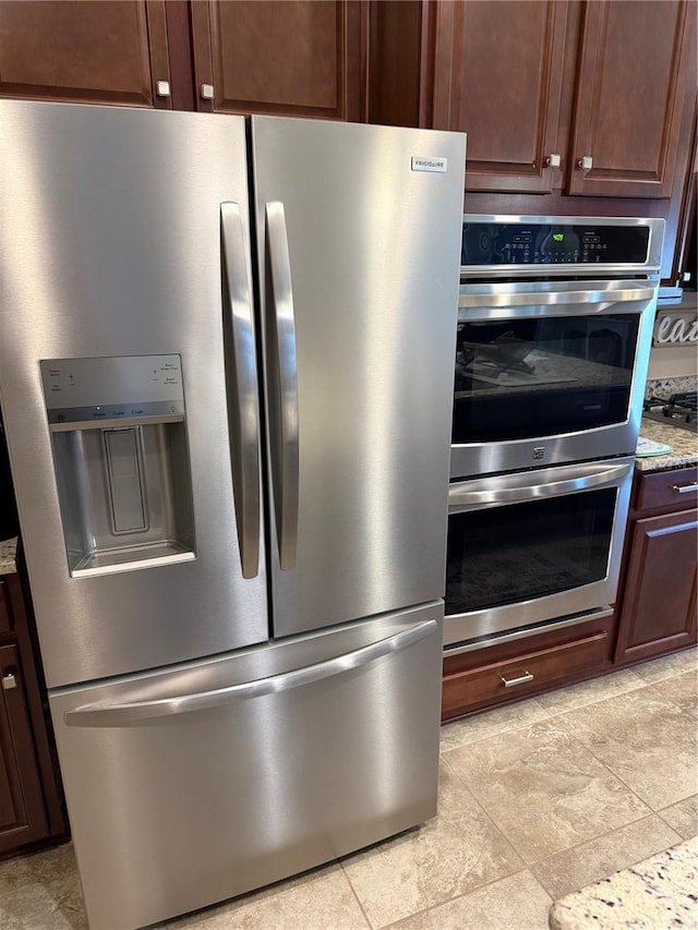 room details with light stone countertops, stainless steel appliances, and dark brown cabinets