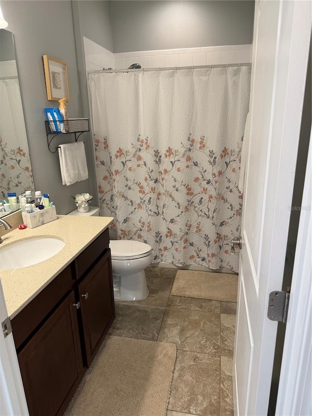 full bathroom with toilet, stone finish floor, vanity, and a shower with shower curtain