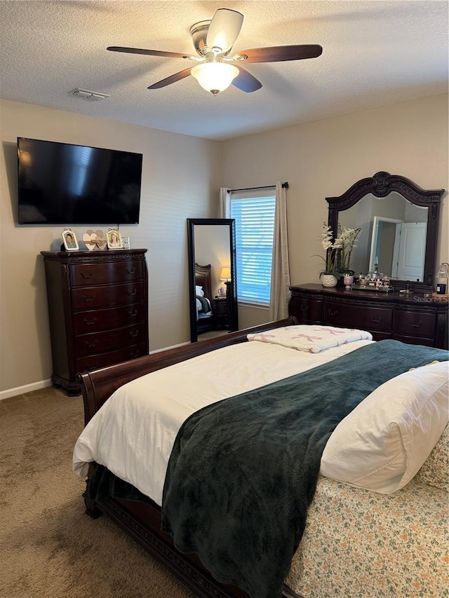 bedroom featuring a textured ceiling, visible vents, a ceiling fan, and carpet floors
