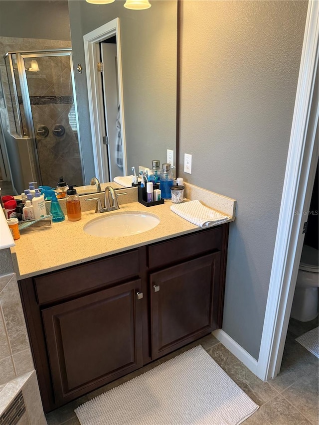 bathroom with toilet, vanity, a stall shower, and baseboards
