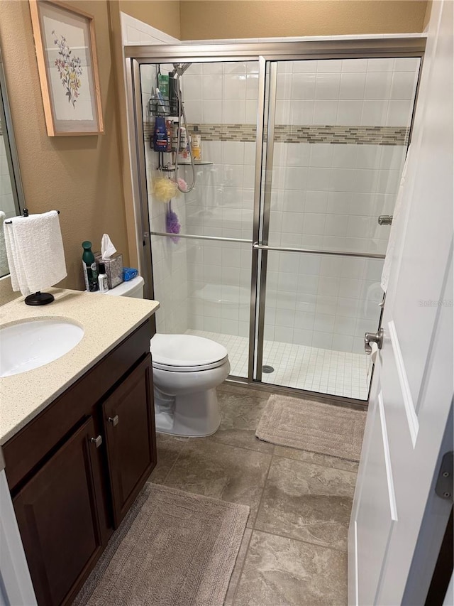 full bathroom featuring a stall shower, toilet, and vanity