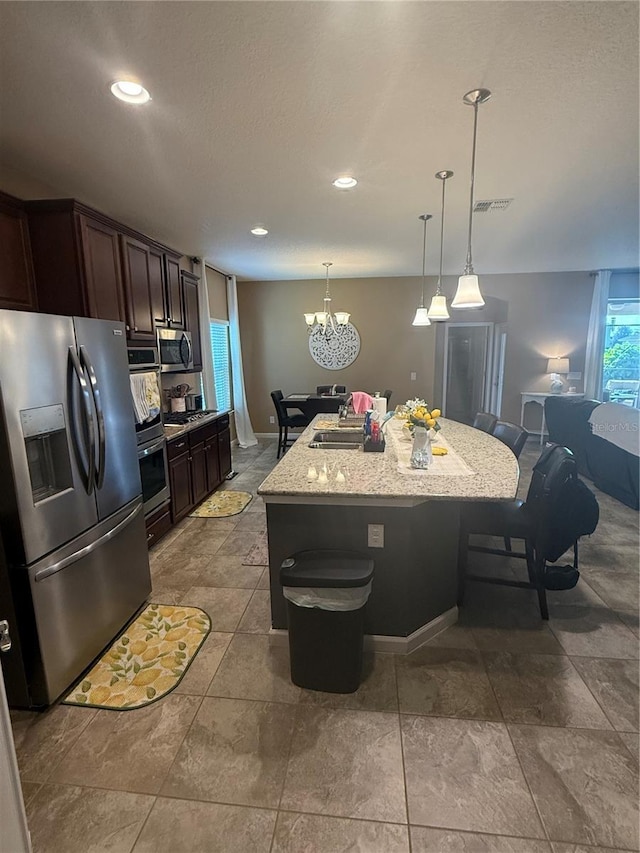 2504 Cavender Creek Rd, Minneola, FL 34715 - kitchen featuring stainless steel appliances, a center island, dark brown cabinetry, a chandelier, and hanging light fixtures