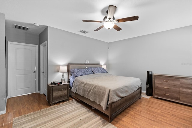bedroom featuring baseboards, visible vents, wood finished floors, and ceiling fan