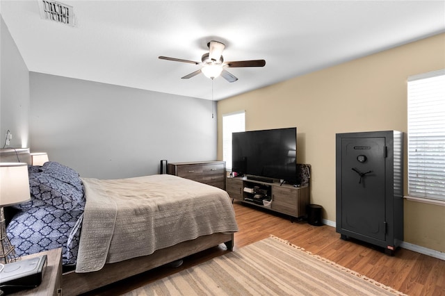 bedroom with visible vents, baseboards, light wood finished floors, and multiple windows