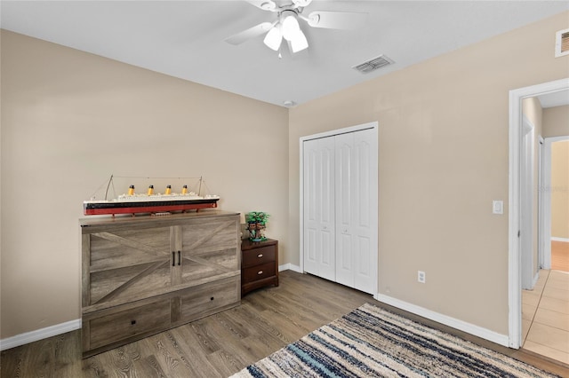 bedroom with wood finished floors, visible vents, a closet, and baseboards