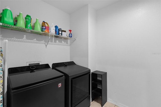 laundry room featuring light tile patterned floors, separate washer and dryer, laundry area, and baseboards