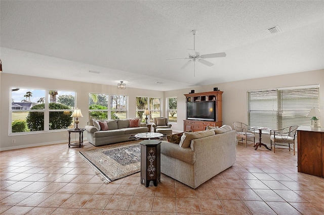 living area with light tile patterned floors, baseboards, visible vents, a ceiling fan, and a textured ceiling