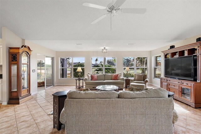 living area with light tile patterned floors, a ceiling fan, and baseboards