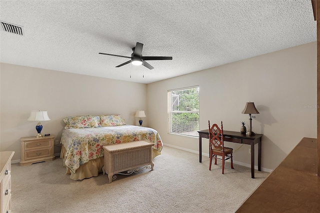 bedroom with a ceiling fan, visible vents, light carpet, baseboards, and a textured ceiling