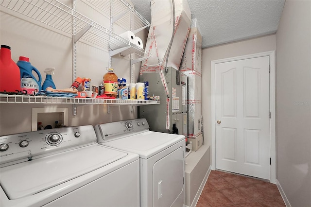 clothes washing area with a textured ceiling, independent washer and dryer, laundry area, and baseboards