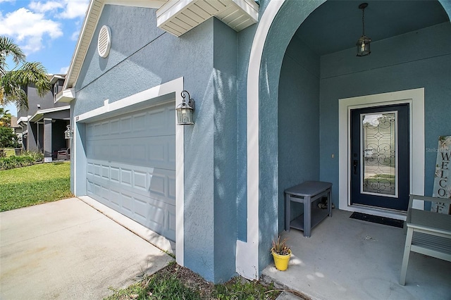 entrance to property featuring stucco siding, concrete driveway, and a garage