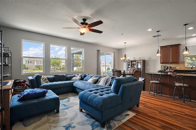 living room with recessed lighting, ceiling fan with notable chandelier, visible vents, a textured ceiling, and dark wood-type flooring