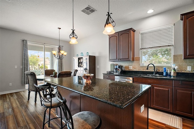 kitchen with stainless steel dishwasher, dark wood finished floors, a sink, and visible vents