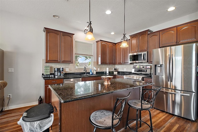 kitchen with dark wood-style flooring, decorative backsplash, stainless steel appliances, and a kitchen island