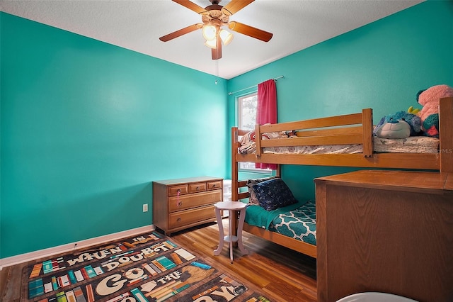 bedroom featuring baseboards, wood finished floors, and ceiling fan