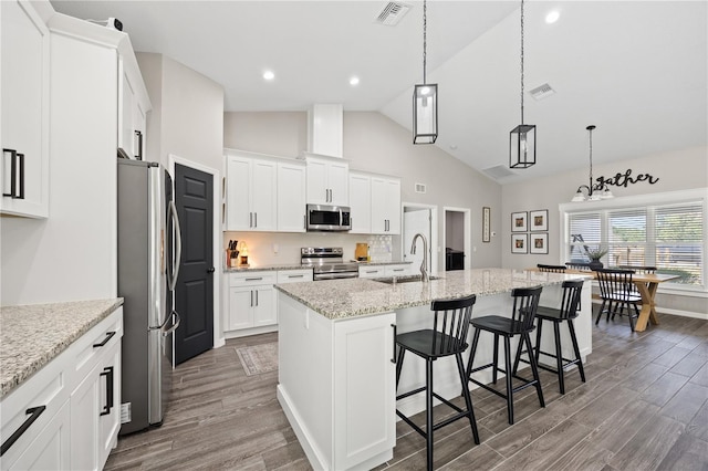 kitchen with wood finished floors, visible vents, stainless steel appliances, and a sink