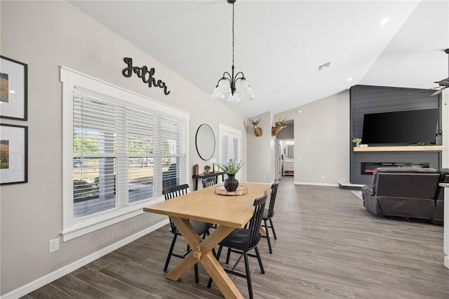 dining space featuring a notable chandelier, lofted ceiling, visible vents, baseboards, and wood finished floors