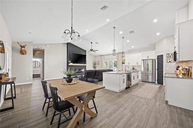 dining space with visible vents, light wood-type flooring, and ceiling fan with notable chandelier