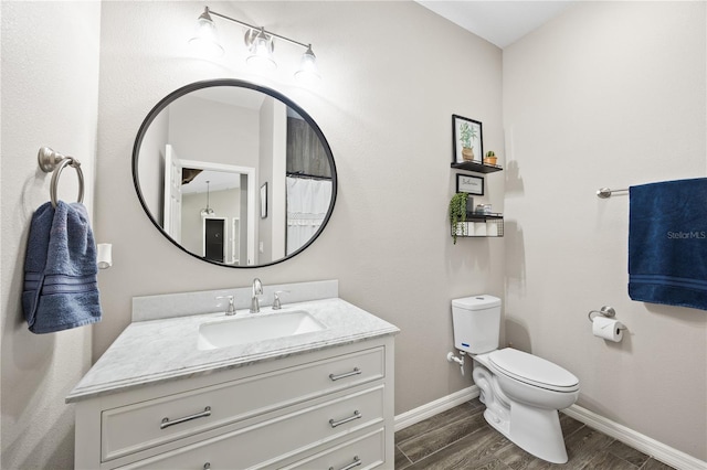 bathroom featuring toilet, vanity, wood finished floors, and baseboards