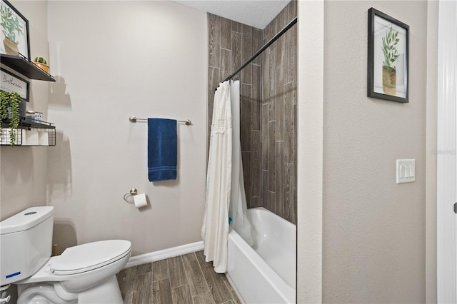 bathroom with baseboards, shower / bath combo, wood finished floors, and toilet