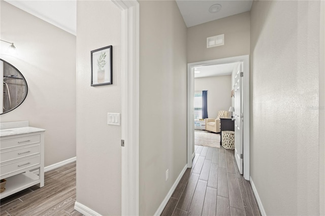hallway featuring dark wood-style floors, visible vents, and baseboards