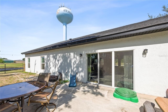 rear view of property featuring fence, outdoor dining area, stucco siding, and a patio area