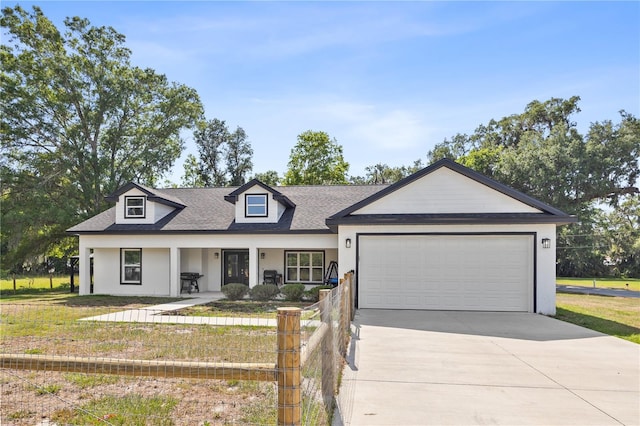 view of front facade with a porch, a front yard, a shingled roof, driveway, and an attached garage
