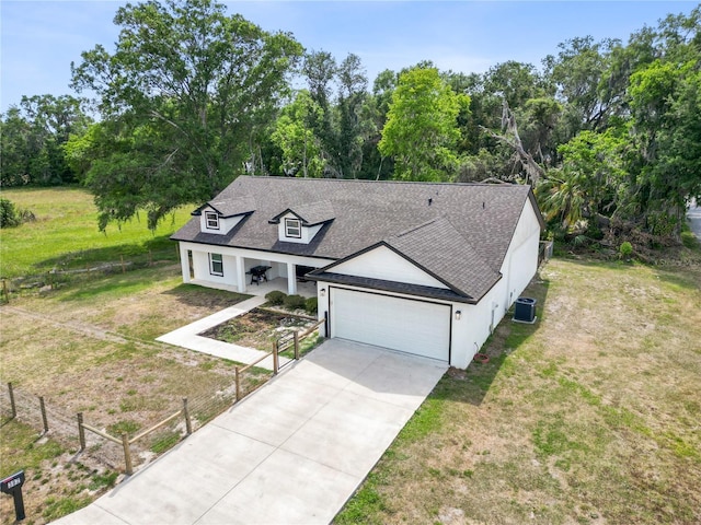 view of front of home with a garage, cooling unit, a front yard, and roof with shingles