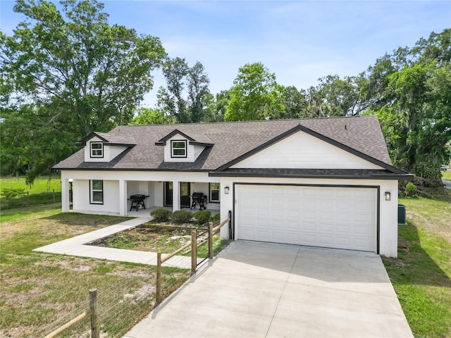 view of front facade with stucco siding, driveway, roof with shingles, a front lawn, and an attached garage