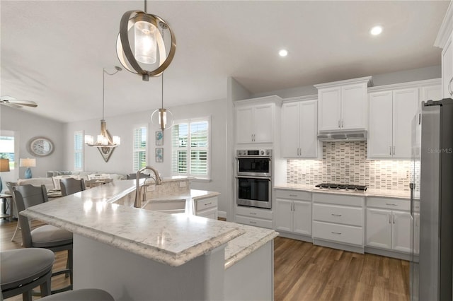 8492 Hartford Way, Mount Dora, FL 32757 - kitchen featuring stainless steel appliances, dark wood-type flooring, a breakfast bar, decorative backsplash, and white cabinets