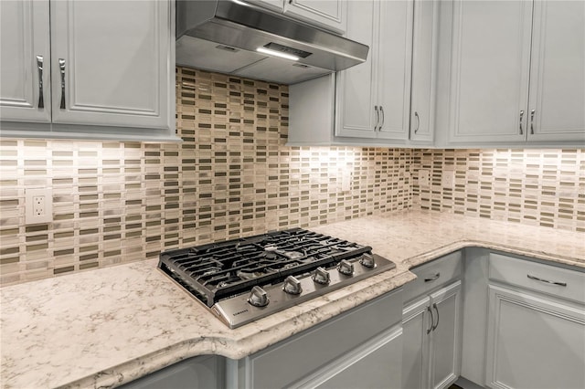 8492 Hartford Way, Mount Dora, FL 32757 - kitchen with under cabinet range hood, stainless steel gas stovetop, tasteful backsplash, and light stone countertops