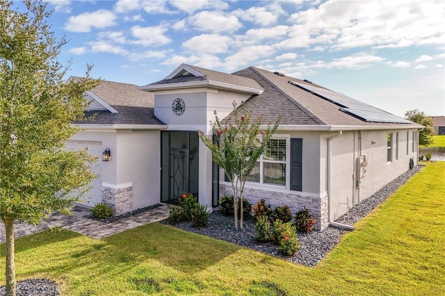 8492 Hartford Way, Mount Dora, FL 32757 - ranch-style house featuring stucco siding, stone siding, a front yard, a shingled roof, and roof mounted solar panels
