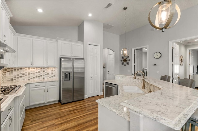 8492 Hartford Way, Mount Dora, FL 32757 - kitchen with stainless steel appliances, vaulted ceiling, wood finished floors, backsplash, and white cabinets