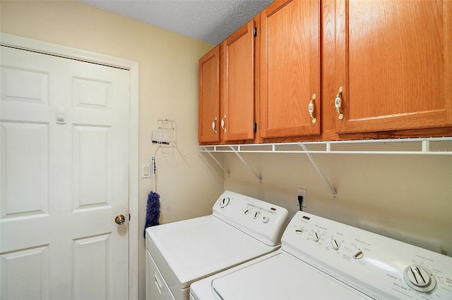 washroom with a textured ceiling, cabinet space, and washer and clothes dryer
